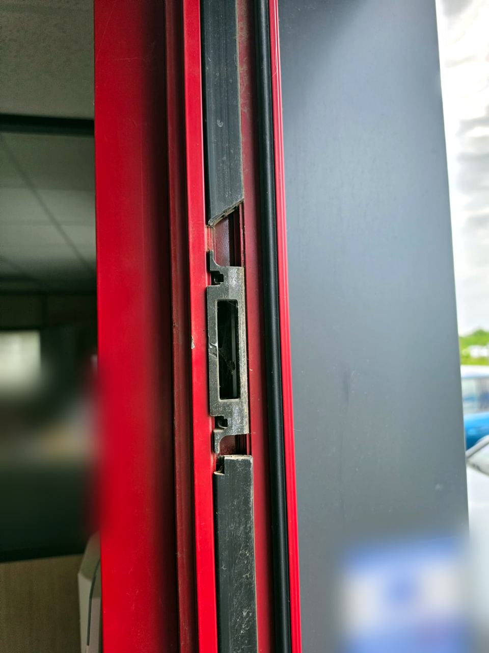 Gâche et mécanisme de serrure multipoints usés sur une porte professionnelle en aluminium
